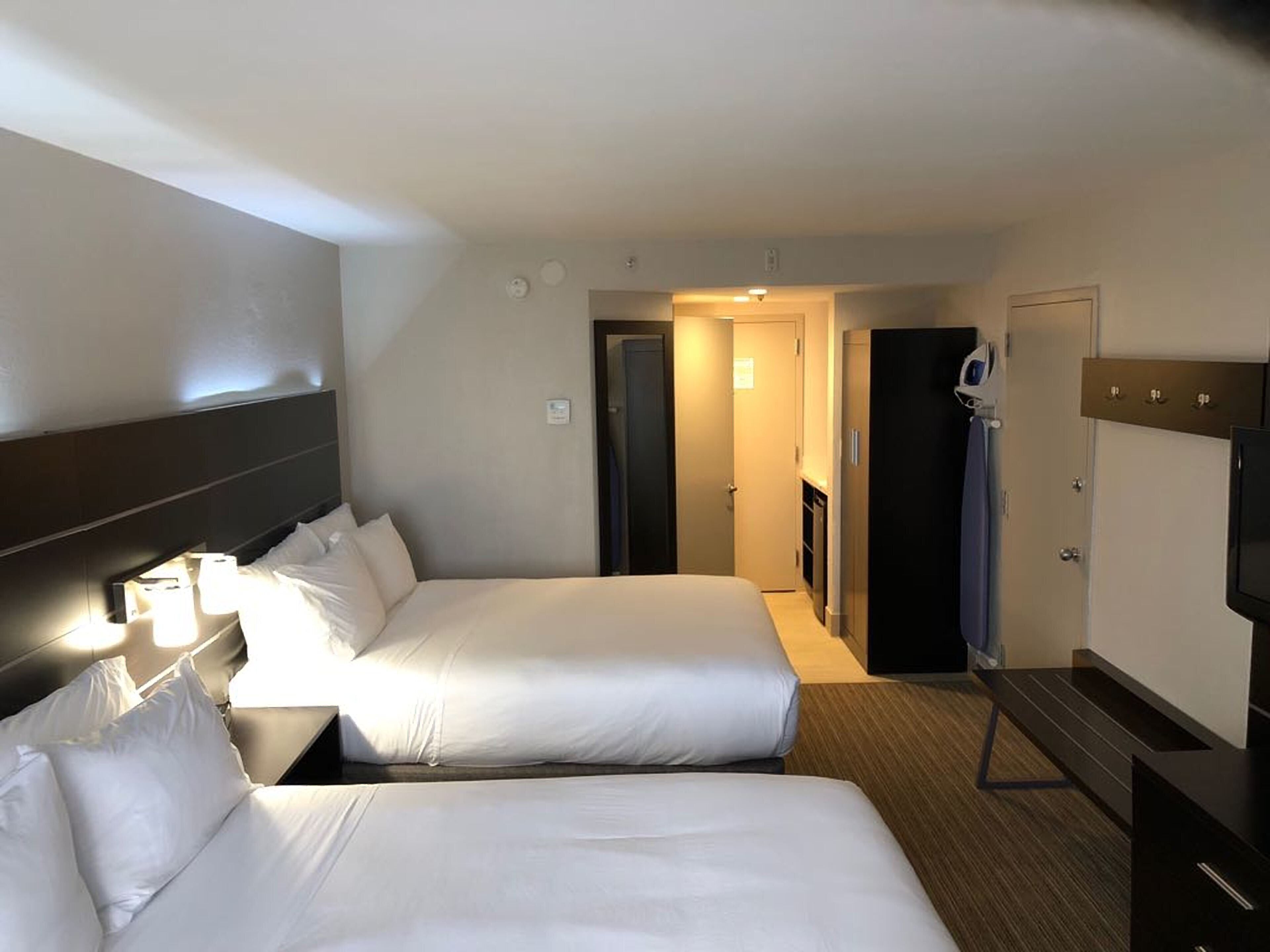 A hotel room with two beds, a TV, and a wardrobe.