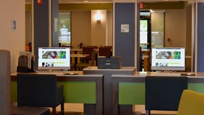 A reception area with two computer monitors displaying content, a reception desk, and a seating area with chairs.