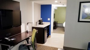 A modern office space with a desk, chair, and a large flat-screen TV.