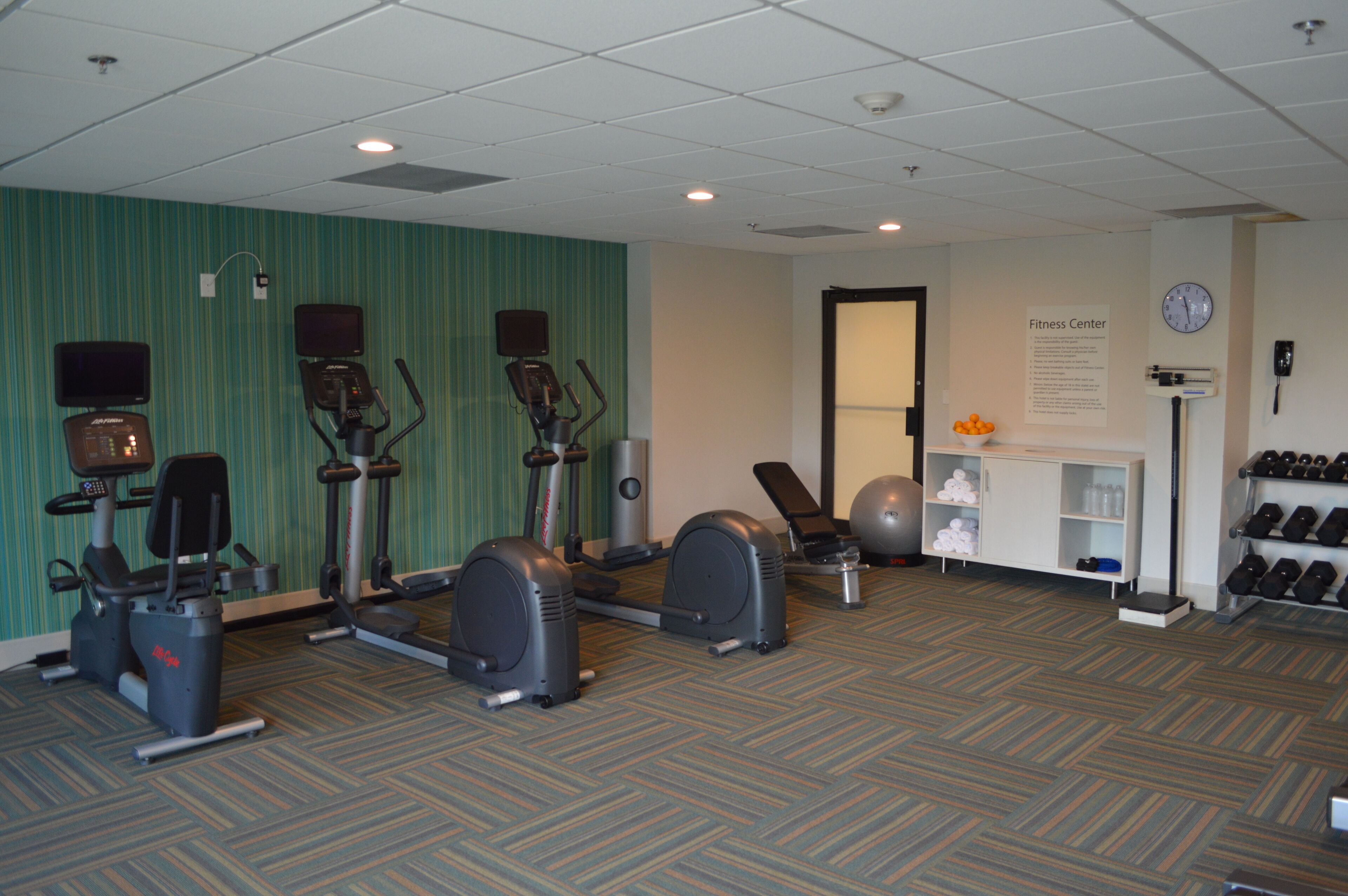Ein Fitnessstudio mit Laufbändern, Crosstrainern und einer Gewichtstation.