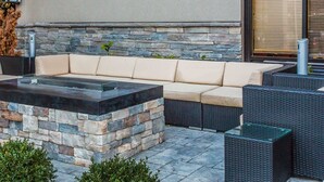 An outdoor seating area with a stone fire feature, a sofa, and wicker furniture. - Quality Suites Nashville Airport (Nashville)