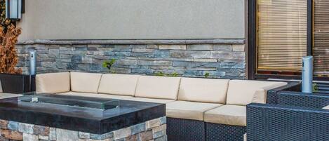 An outdoor seating area with a stone fire feature, a sofa, and wicker furniture.