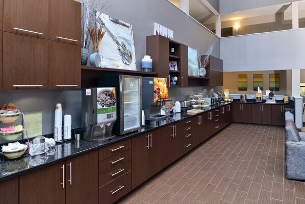 A modern kitchen with dark wood cabinets, stainless steel appliances, and a long countertop.