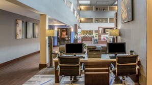 A hotel lobby with a reception desk, two computer workstations, and a seating area with chairs. - Quality Suites Nashville Airport (Nashville)
