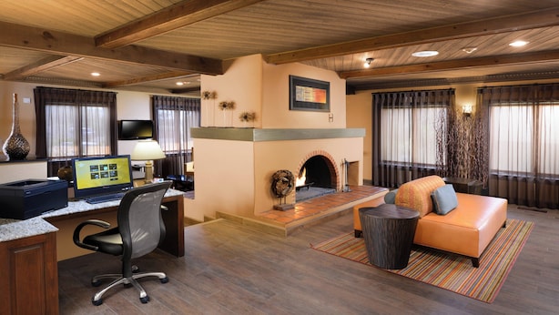 A spacious living area with a fireplace, a comfortable sofa, a desk with a computer, and a television. - Residence Inn by Marriott Santa Fe (Santa Fe)