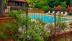 A swimming pool with a fence, surrounded by greenery and a building with a red roof. - Residence Inn by Marriott Santa Fe (Santa Fe)
