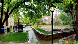 A courtyard with a stone pathway, a small lawn, and a tennis court. - Residence Inn by Marriott Santa Fe (Santa Fe)