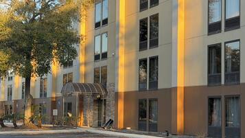 A multi-story hotel with a modern design, featuring a covered entrance, large windows, and a parking lot.