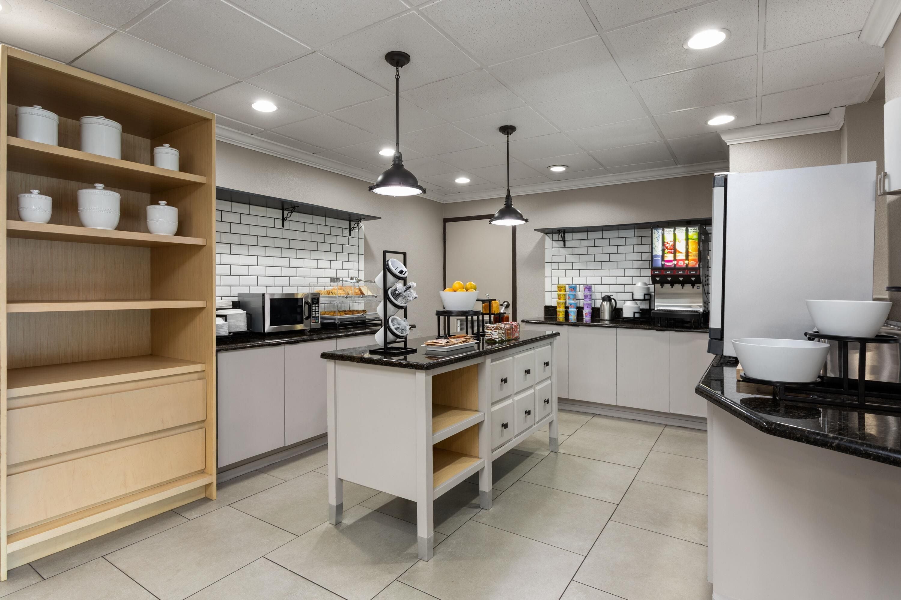 A modern kitchen with white cabinets, black countertops, and a central island.