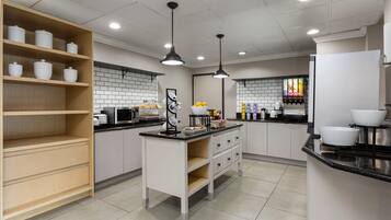 A modern kitchen with white cabinets, black countertops, and a central island.