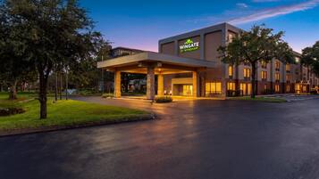 A Wingate by Wyndham hotel with a modern design, featuring a covered entrance and a well-maintained lawn.