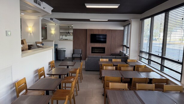 Un restaurante con varias mesas y sillas, un televisor y una chimenea.