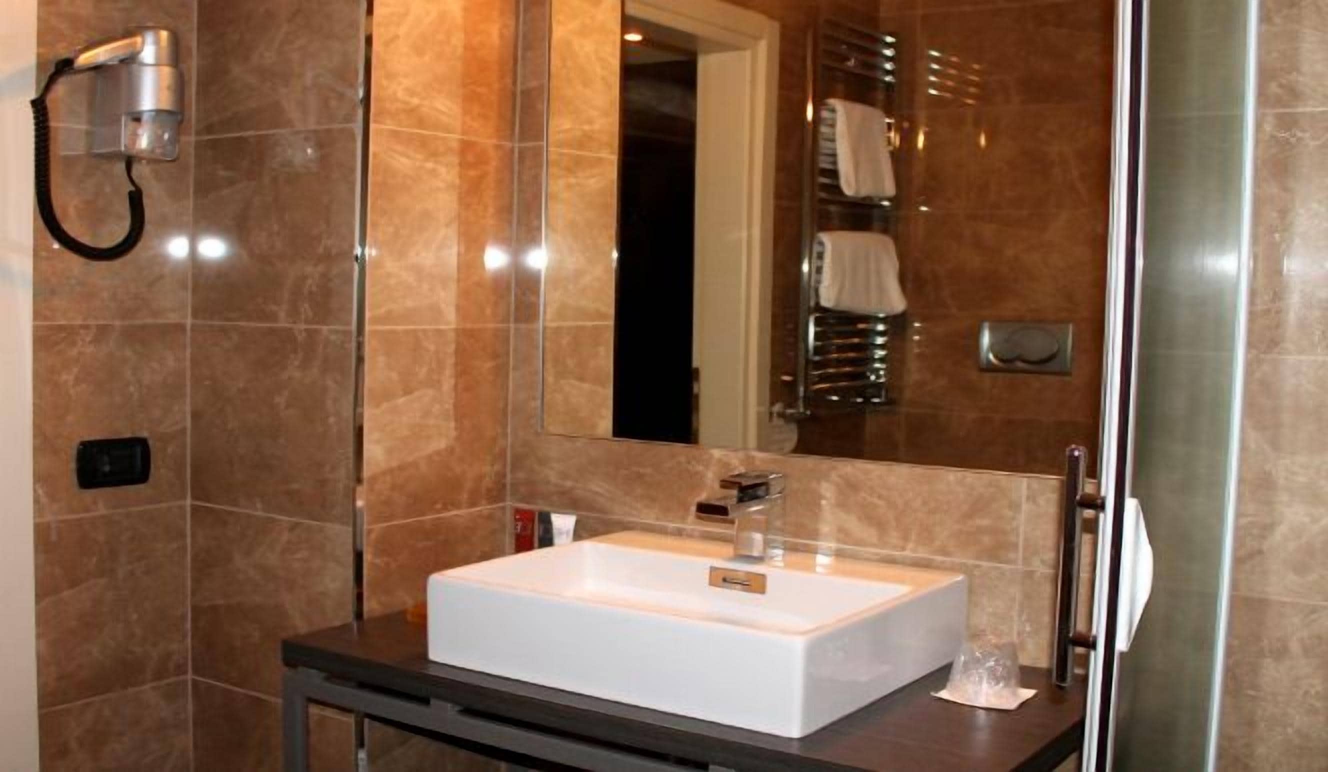 A modern bathroom with a white sink, a mirror, and a towel rack.