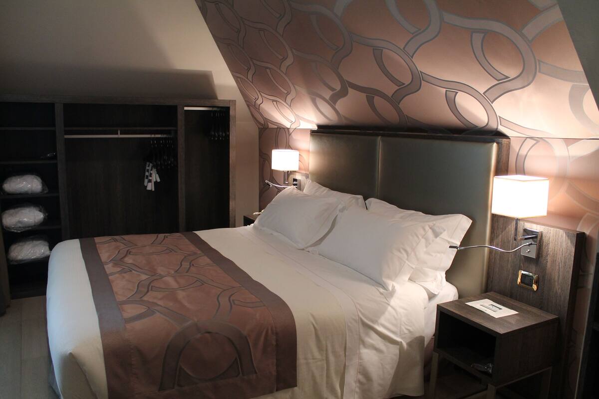 Een hotelkamer met een groot bed, een kledingkast en twee bedlampjes.