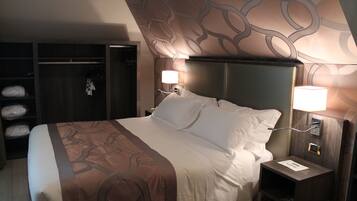 A hotel room with a large bed, a wardrobe, and two bedside lamps.