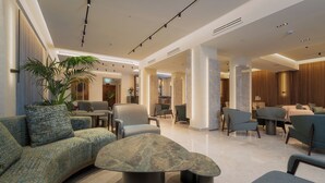 Un lobby moderno con zonas de estar, una mesa de centro y una planta grande.