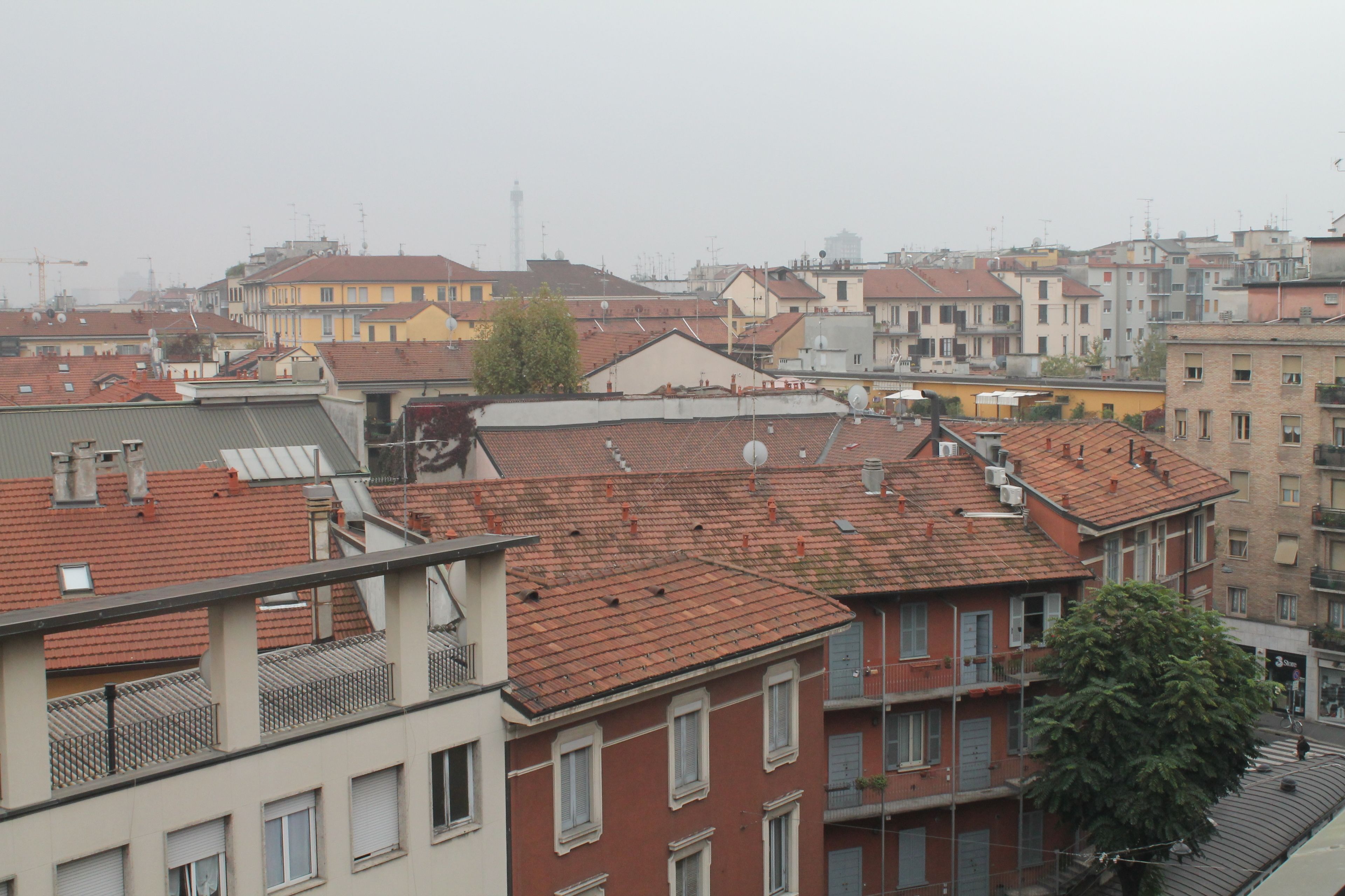 Une rangée d’immeubles à plusieurs étages, avec des toits recouverts de tuiles rouges, des balcons et des antennes paraboliques.