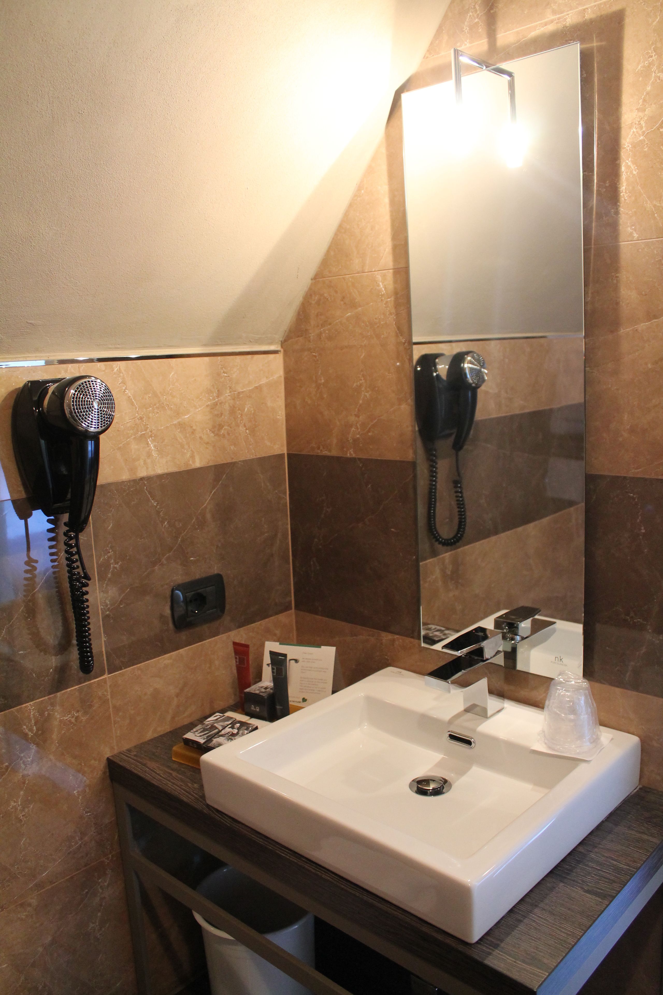 Casa de banho com uma sanita branca, um secador de cabelo e um telefone.