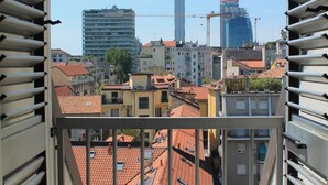 Vista desde un balcón con barandas metálicas, sobre un paisaje urbano con diversos edificios, incluyendo un rascacielos en construcción.
