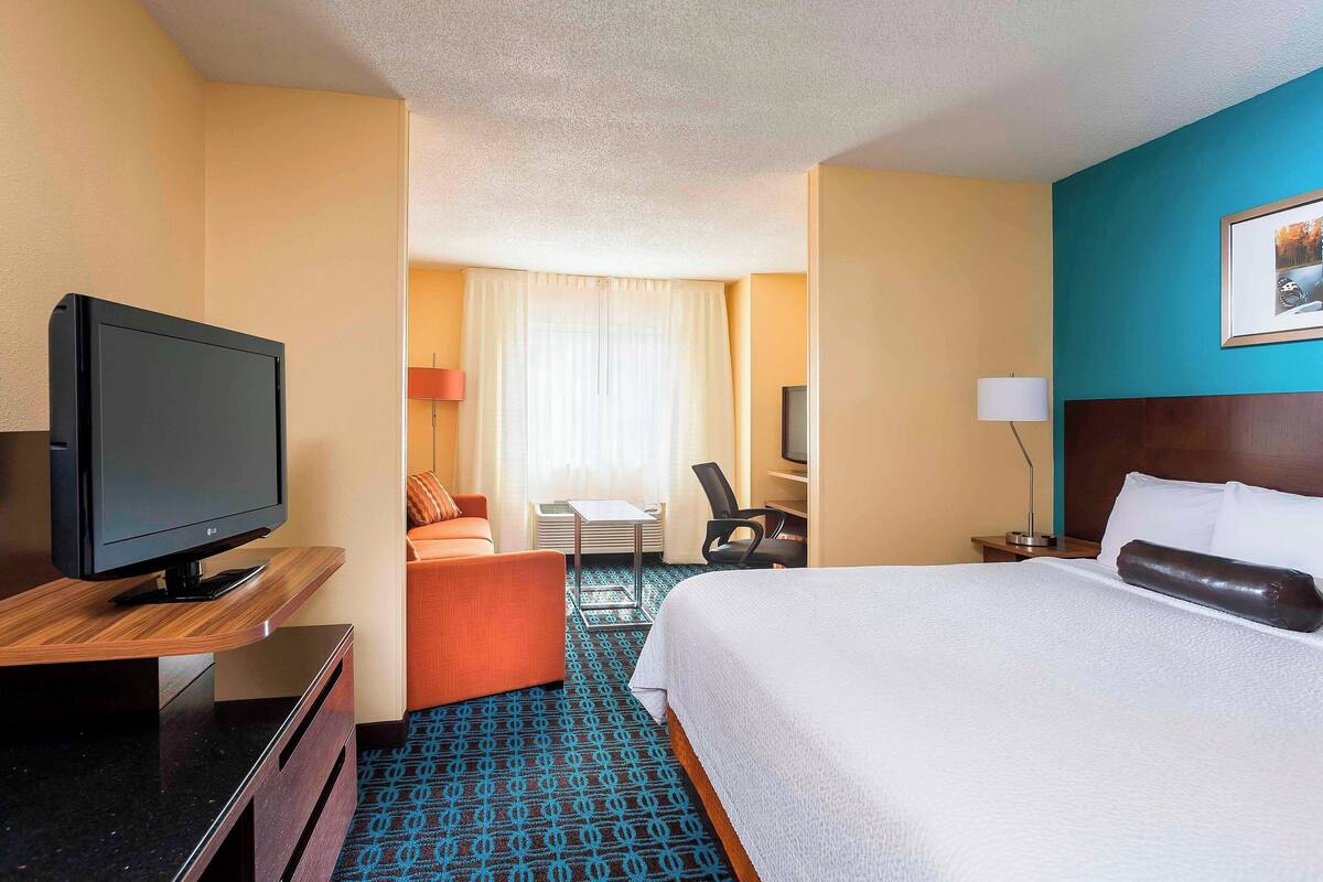 Ein Hotelzimmer mit Bett, Fernseher, Schreibtisch und Stuhl.