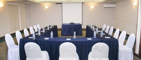 A conference room with a long table, white chairs, and water bottles.