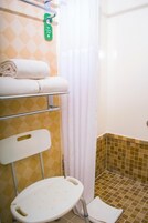 Un baño con ducha, inodoro y un estante con toallas.