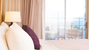 A hotel room with a large bed, a nightstand with a lamp, and a view of a balcony with a cityscape. - iStay Hotel Ciudad Juarez (Ciudad Juárez)
