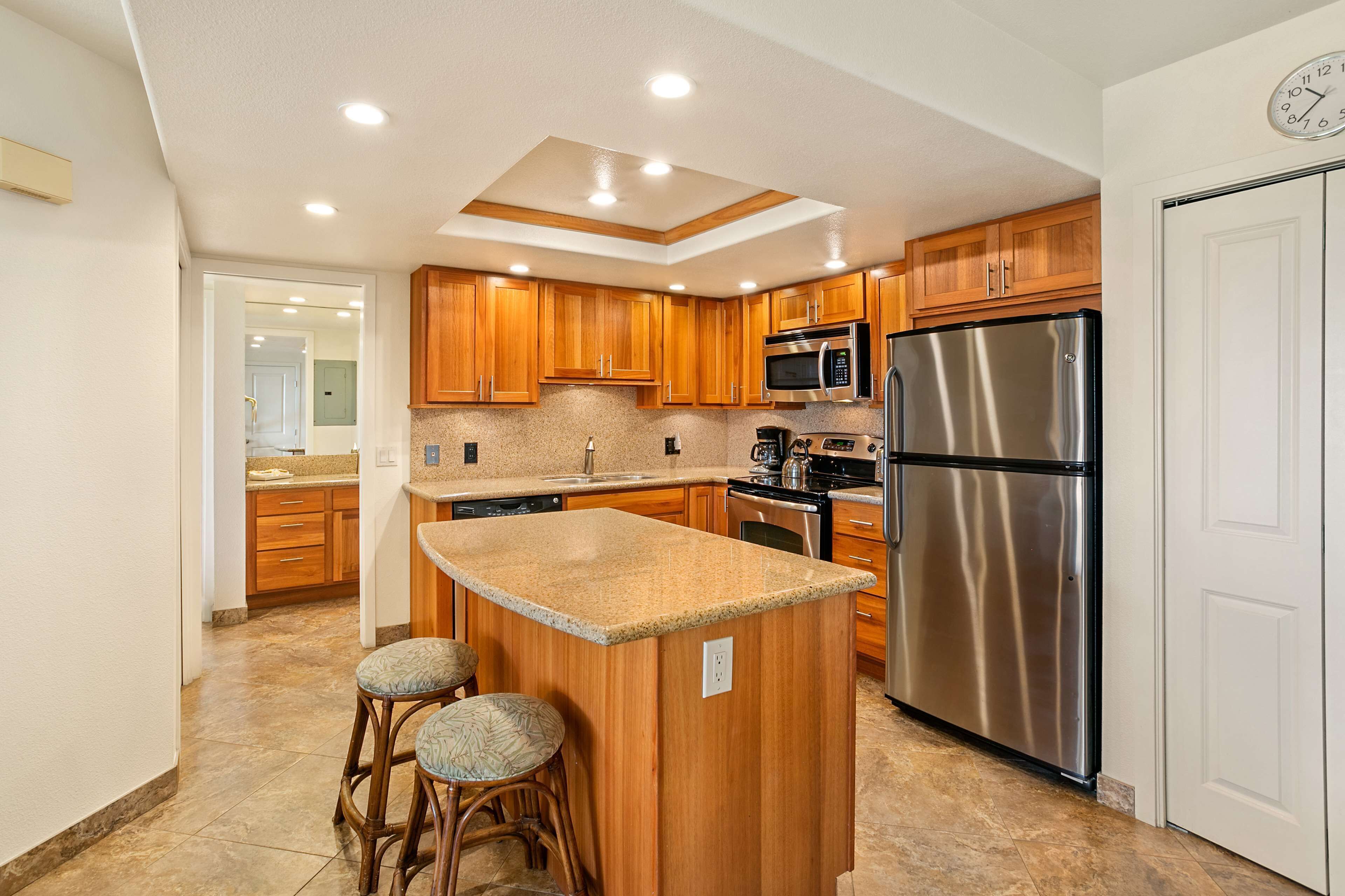 Una cocina moderna con armarios de madera, electrodomésticos de acero inoxidable y una isla central con taburetes.