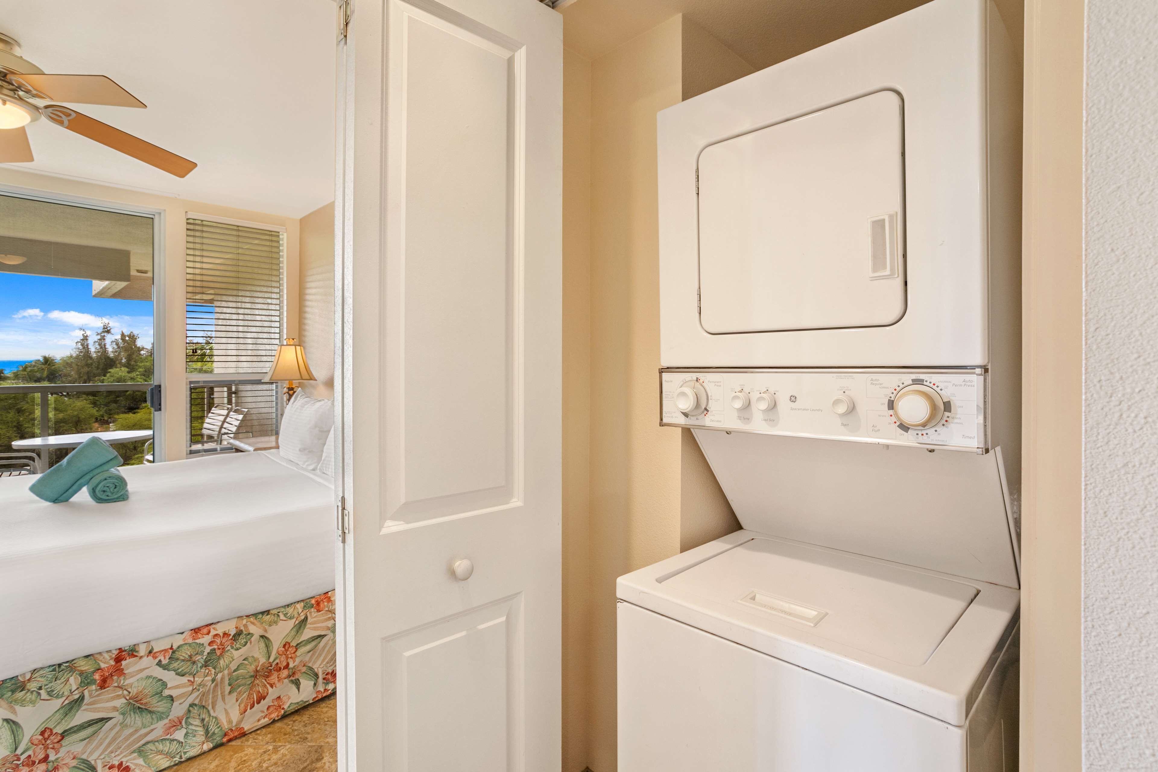 A laundry room with a washer and dryer, a bed with a view, and a ceiling fan.
