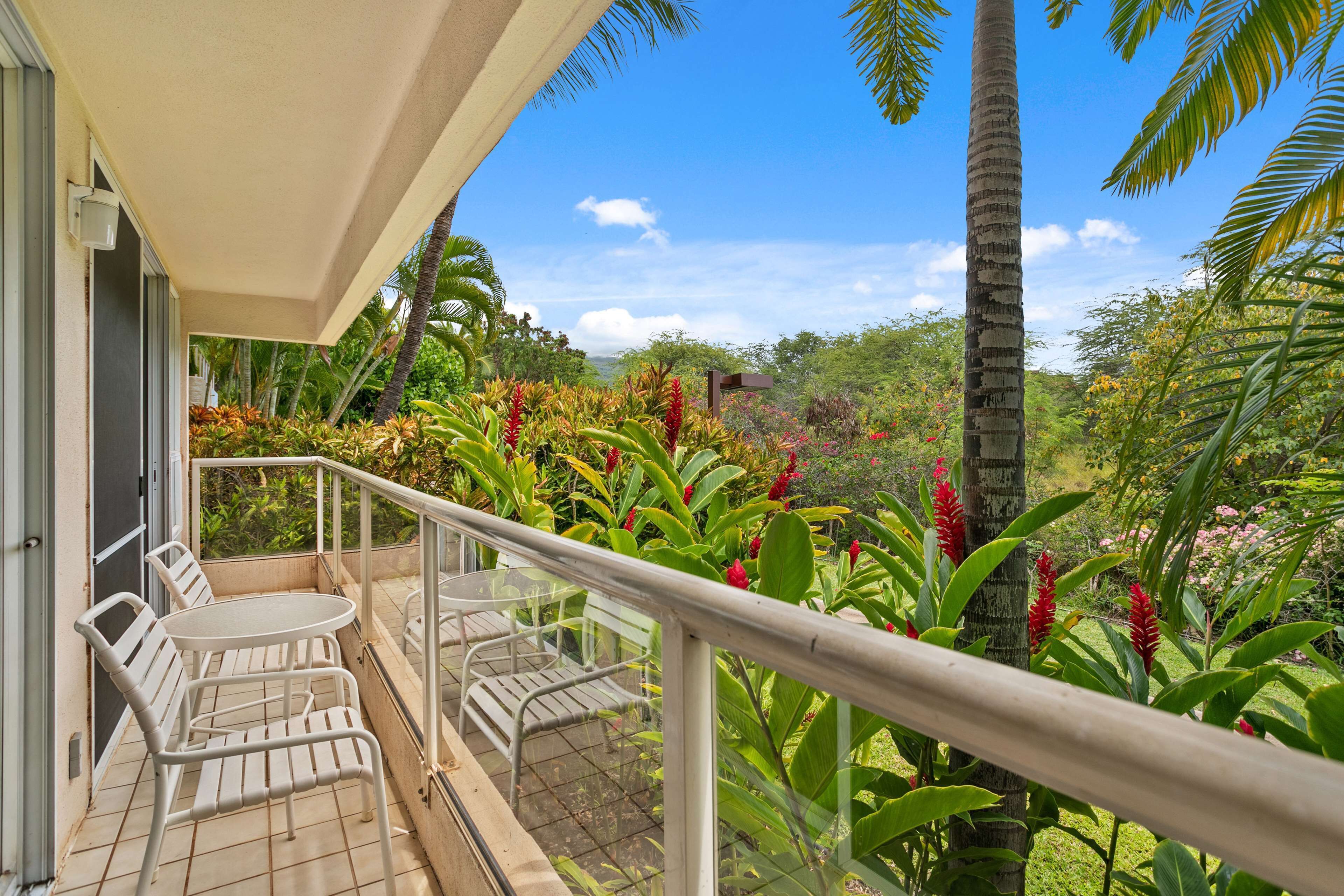 Varanda com mesa e cadeiras, rodeada por plantas tropicais exuberantes e uma vista deslumbrante da paisagem.
