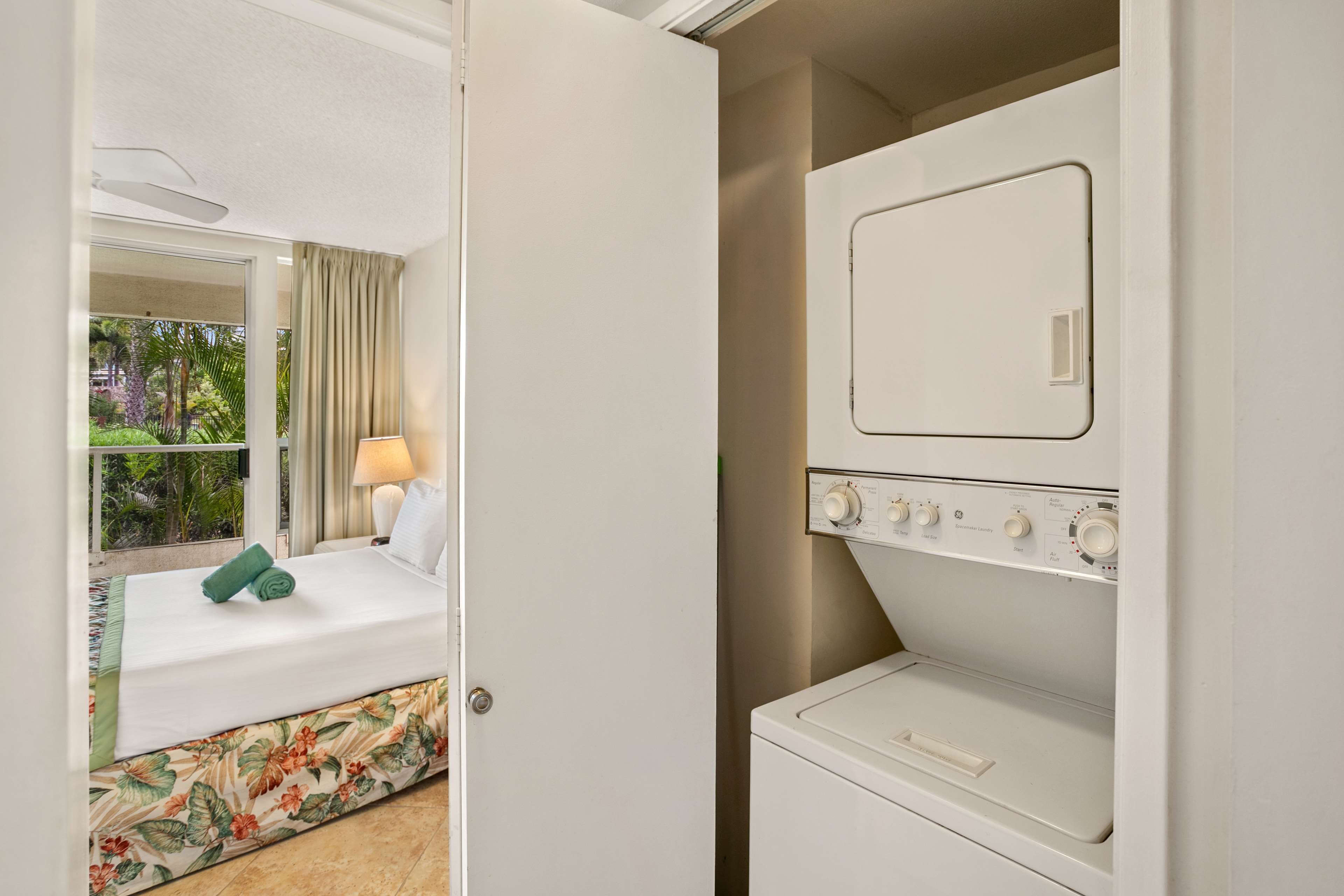 Una camera d'albergo con un letto, una finestra con tende e una lavatrice.
