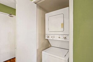 Une buanderie équipée d’un lave-linge et d’un sèche-linge à chargement frontal, d’une porte et d’un mur vert.