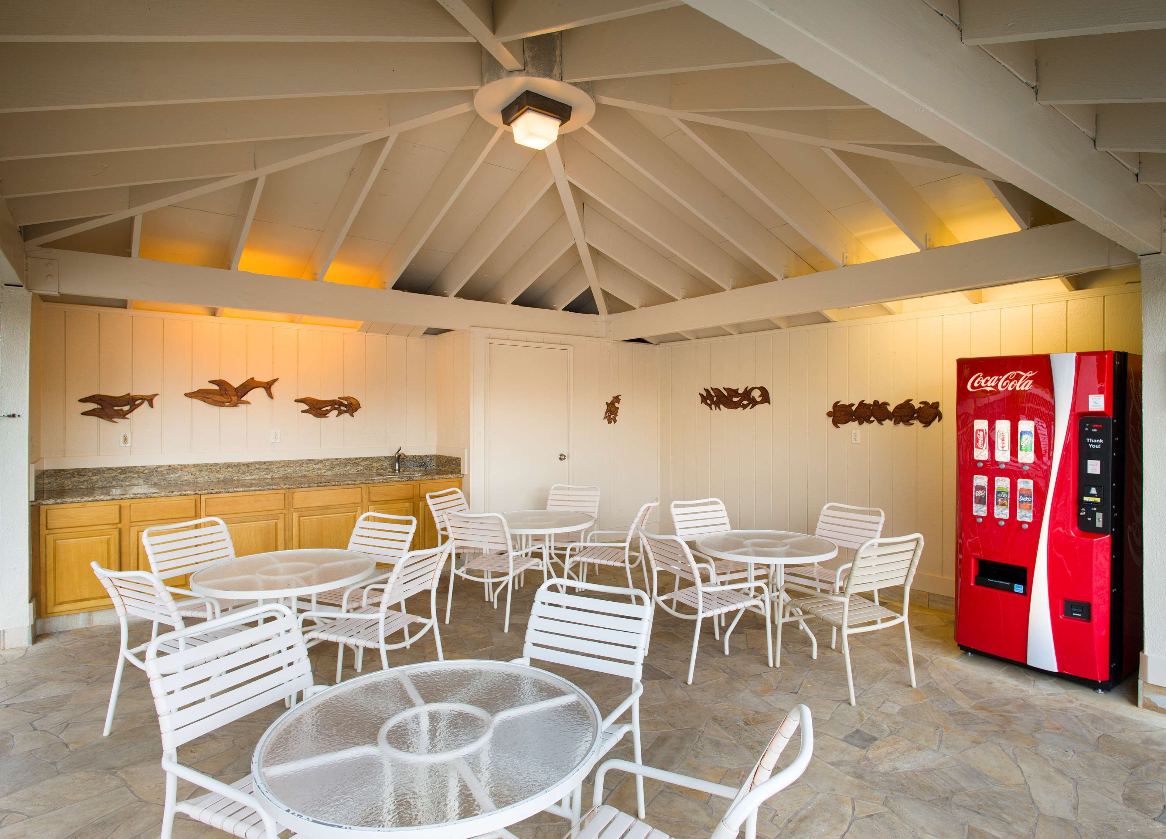 A spacious indoor area with white furniture, a kitchen area, and a Coca-Cola vending machine.
