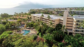Een resort met een zwembad, weelderige begroeiing en uitzicht op de oceaan.