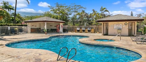 A swimming pool with two small adjacent pools, surrounded by stone tiles and palm trees.