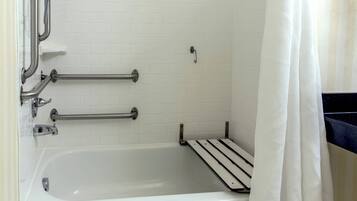 Una bañera blanca con barras de apoyo, una cortina de ducha y una pared de azulejos blancos.