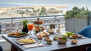 A breakfast table with a variety of foods and drinks, overlooking a beach and ocean view. - Hilton Tel Aviv (Tel Aviv)