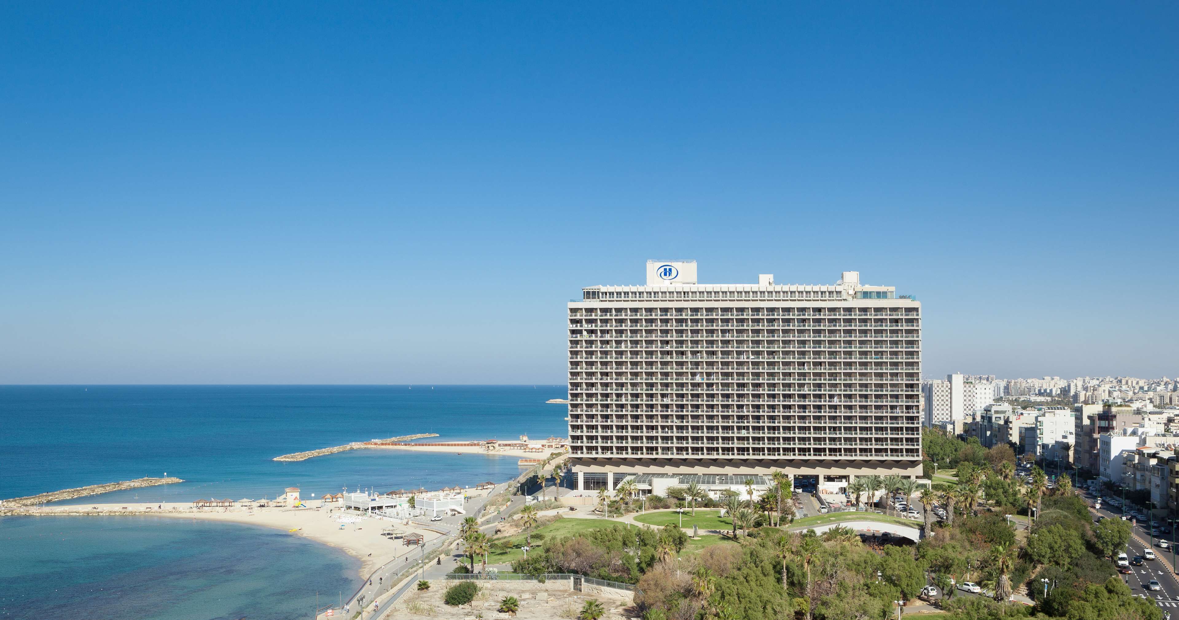 A high-rise hotel with a view of the sea and beach.