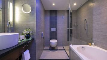A modern bathroom with a large bathtub, a round mirror, and a toilet.