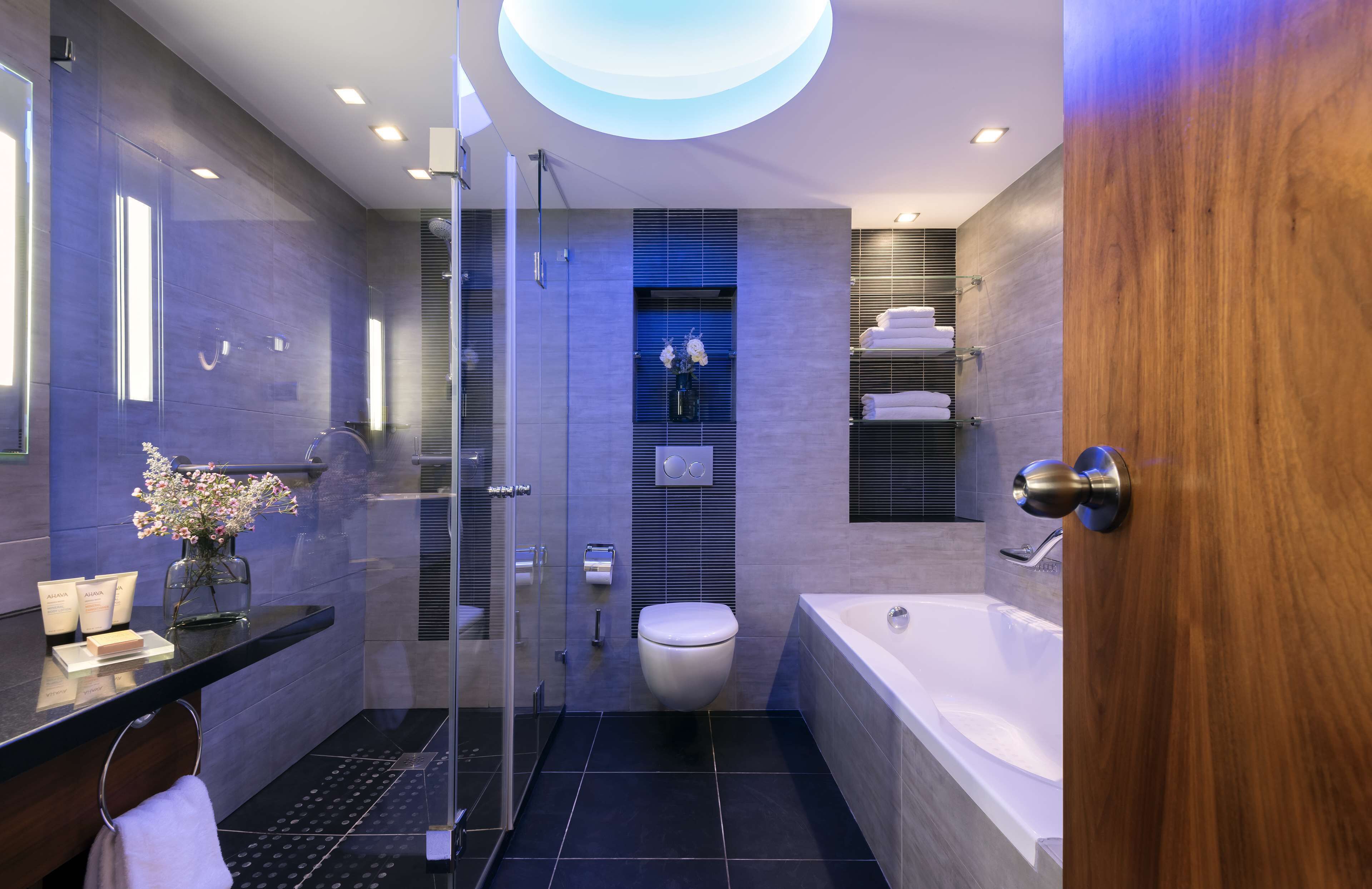 A modern bathroom with a glass shower enclosure, a white toilet, and a bathtub.
