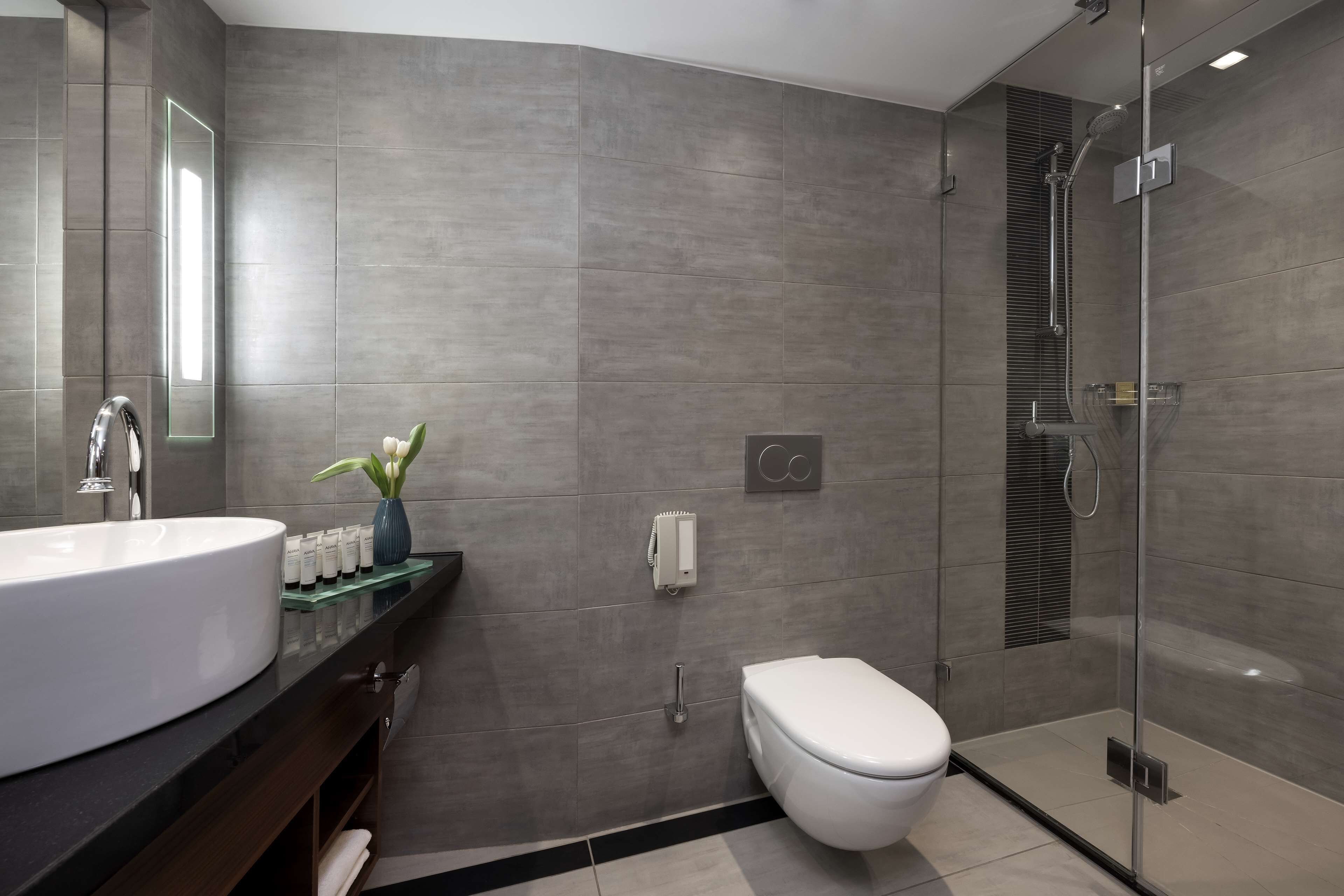A modern bathroom with a large sink, toilet, and glass-enclosed shower.