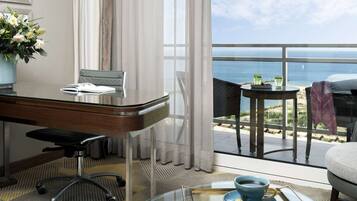 A hotel room with a desk, chair, and a view of the ocean.