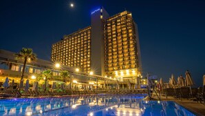 A hotel with a large pool, sun loungers, umbrellas, and palm trees. - Hilton Tel Aviv (Tel Aviv)