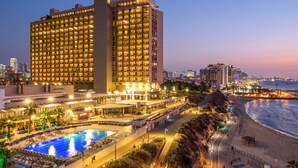 A large hotel with multiple floors, a swimming pool, and a beach area. - Hilton Tel Aviv (Tel Aviv)