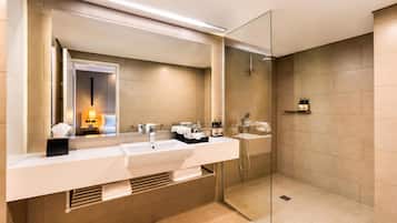 A modern bathroom with a large mirror, two sinks, a shower, and a towel rack.