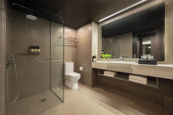 A modern bathroom with a glass-enclosed shower, a toilet, a sink with a mirror, and a towel rack.