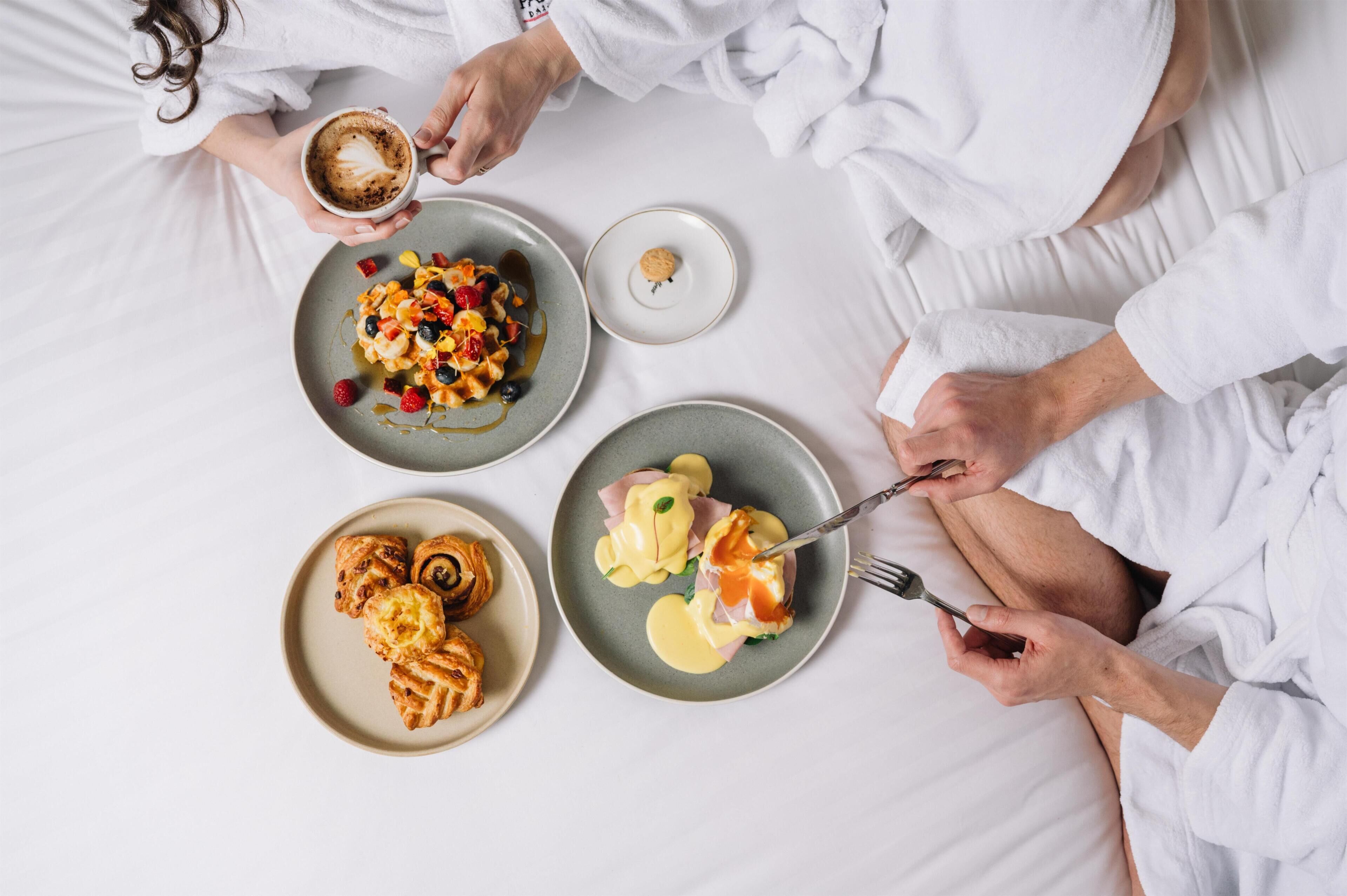 A breakfast setting with plates of food, a coffee cup, and a person in a white robe.