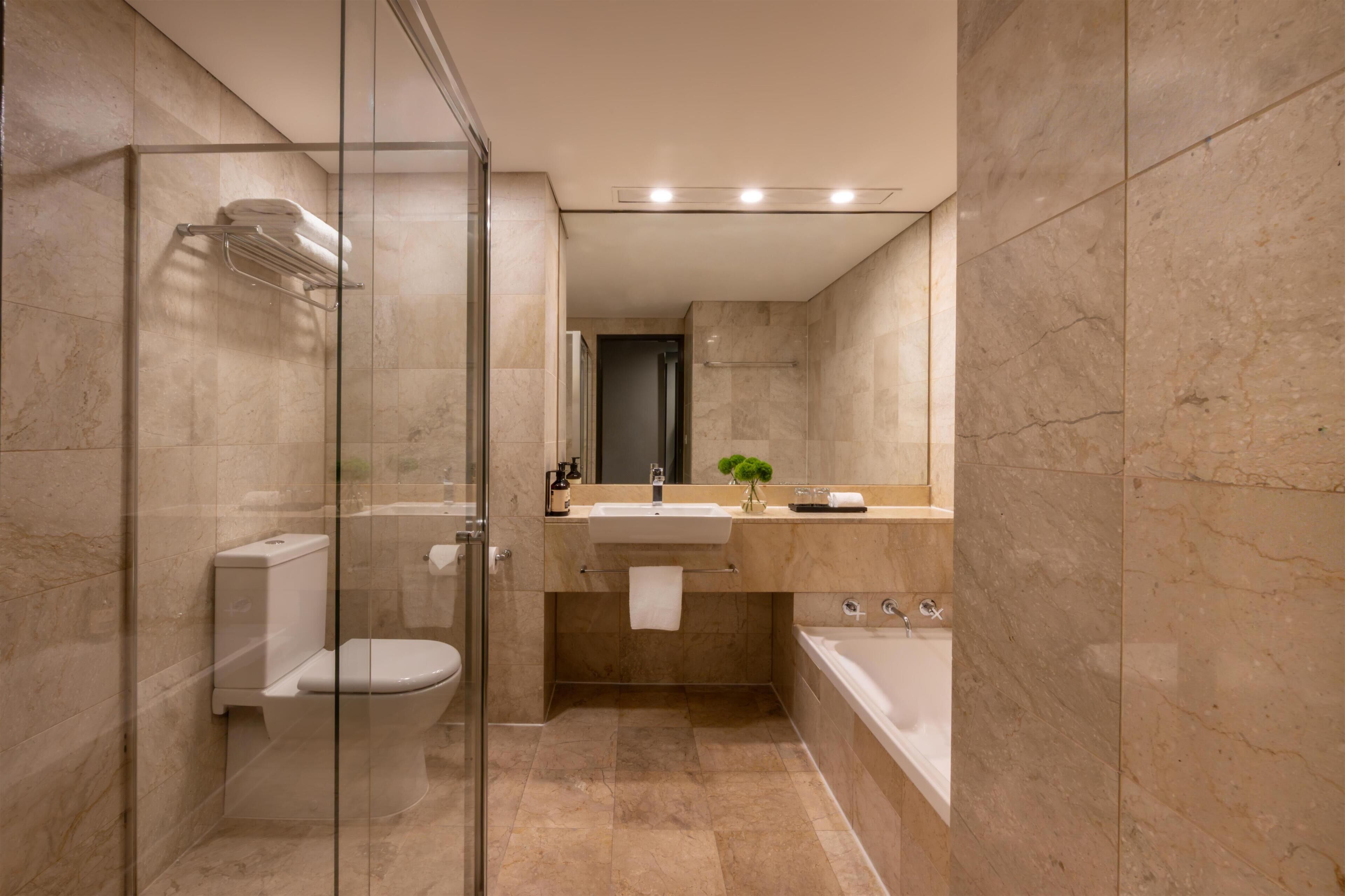 A modern bathroom with a glass shower enclosure, a toilet, a sink, and a bathtub.