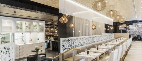 A modern restaurant interior with a long dining area, bar, and kitchen.