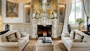A luxurious living room with a fireplace, two sofas, and a coffee table with books.
